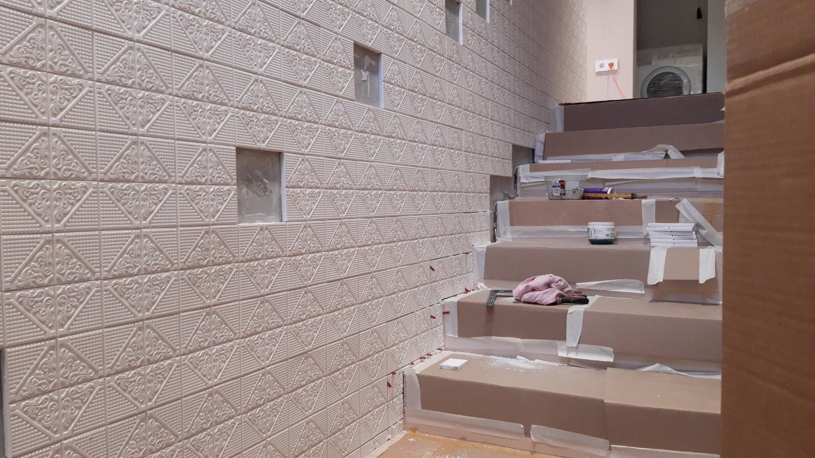 The bespoke patterned wall tiles being laid along the staircase