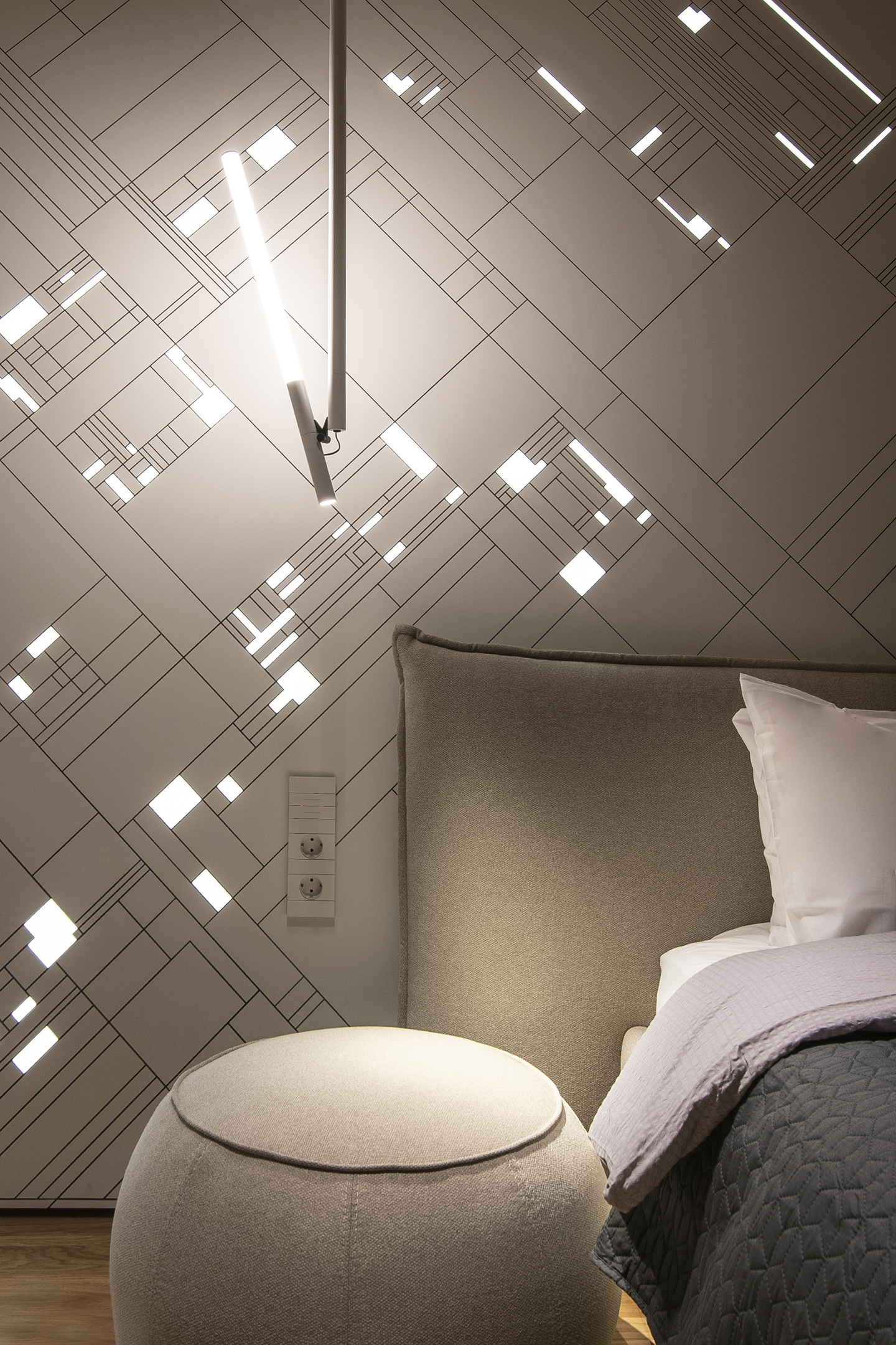 Bedroom wall of diagonal lines and scattered illuminated details behind the bed